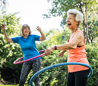 Seniors laughing using hula hoops outdoors